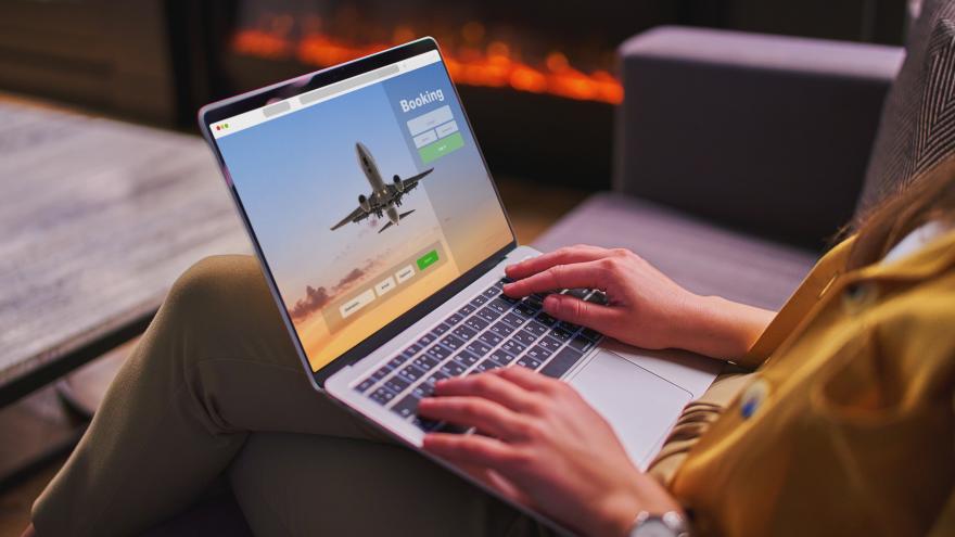 Eine Person sitzt an einem Laptop auf dem ein Flugzeug zu sehen ist. 
